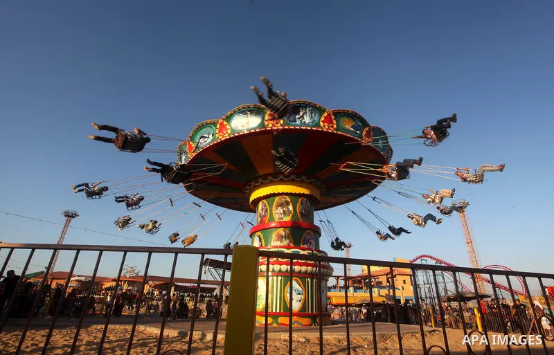 Palestinians enjoy a ride in an amusement park on the third day of Eid al-Fitr, marking the end of Islam's fasting holy month of Ramadan, in Gaza City on August 21, 2012. Photo by Ashraf Amra