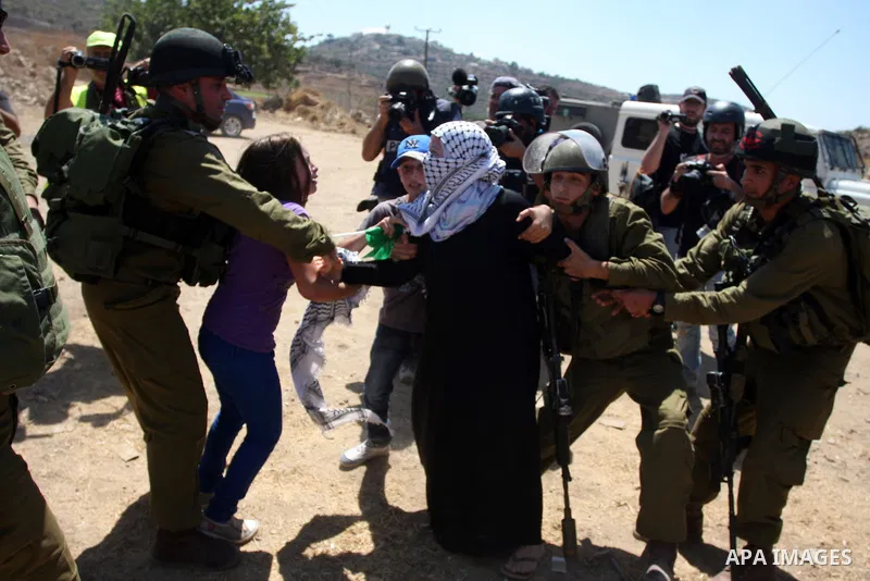 A Palestinian girl holds on to her mother as Israeli soldiers detain her during a demonstration in the West Bank village of Nabi Saleh in protest against the confiscation of Palestinian land to expand the nearby Jewish s...