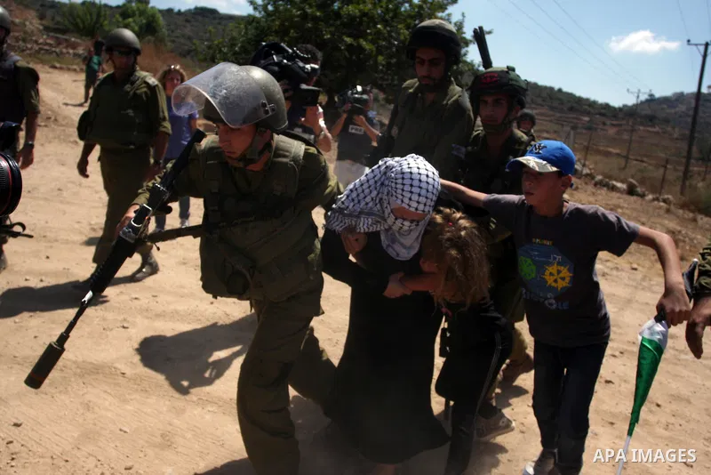 A Palestinian girl holds on to her mother as Israeli soldiers detain her during a demonstration in the West Bank village of Nabi Saleh in protest against the confiscation of Palestinian land to expand the nearby Jewish s...