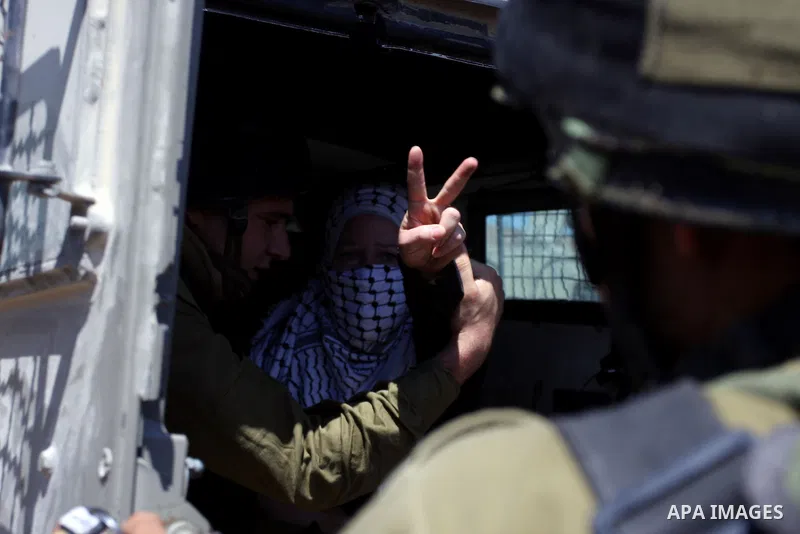 A Palestinian woman flashes the V-sign for victory while being detained by an Israeli soldier in the West Bank village of Nabi Saleh during a protest on August 24, 2012 against the confiscation of Palestinian land to exp...