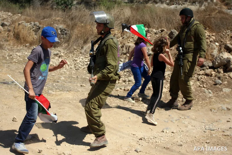 Israeli soldiers stops Palestinian children during a demonstration in the West Bank village of Nabi Saleh in protest against the confiscation of Palestinian land to expand the nearby Jewish settlement of Halamish on Augu...