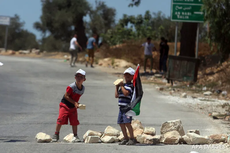 Palestinian children hold national flags and put barriers during a demonstration in the West Bank village of Nabi Saleh in protest against the confiscation of Palestinian land to expand the nearby Jewish settlement of Ha...