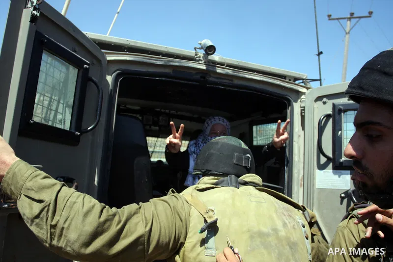 A Palestinian woman flashes the V-sign for victory while being detained by an Israeli soldier in the West Bank village of Nabi Saleh during a protest on August 24, 2012 against the confiscation of Palestinian land to exp...