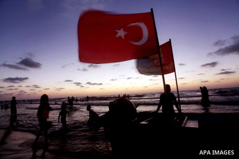 Palestinians hold up Turkish and FC Barcelona soccer team flags on their boat in the sea at Gaza beach during Friday holiday in Gaza city, Aug 24, 2012. Gazans escape to the beach and out from their homes during heat wav...