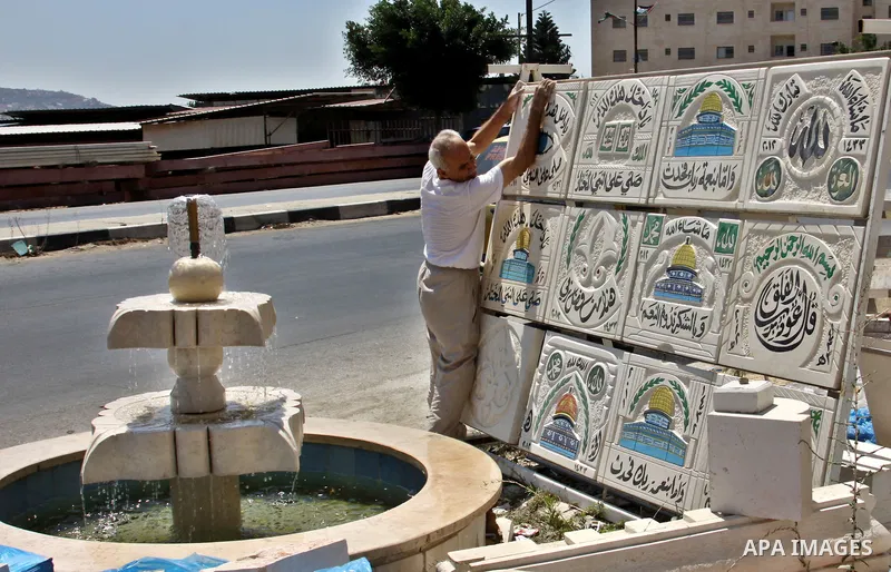 A Palestinian man displays the stones carved out of rock and painted it the Dome of the Rock in order to sell it, in the West Bank City of Nablus, on Aug. 27, 2012. Photo by Nedal Eshtayah