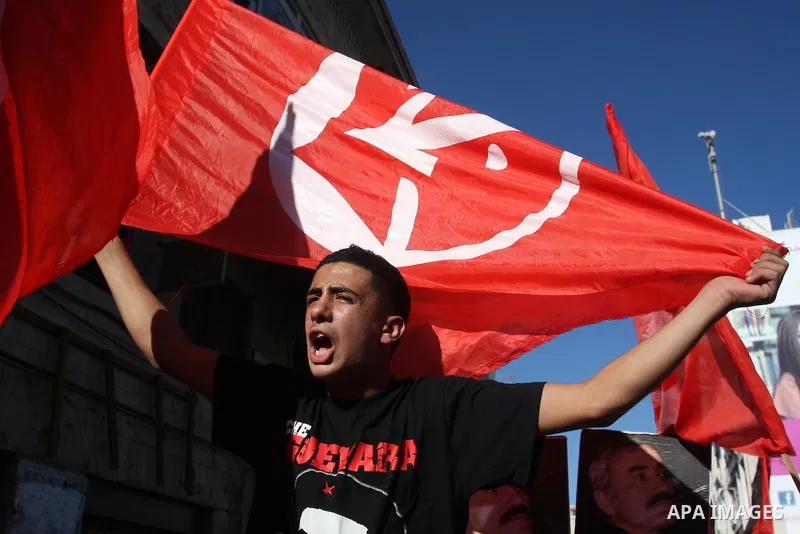 A Palestinian supporter of the Palestinian Front for the Liberation of Palestine (PFLP) waves a red flag during a rally mark the 11th anniversary of the assassination of PFLP leader Abu Ali Mustafa, in the West Bank city...