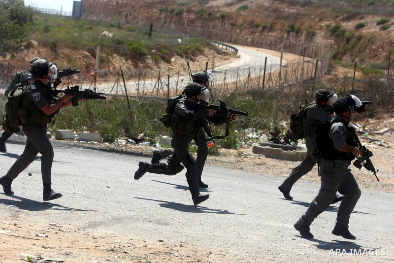 Israeli soldiers run behind Palestinian protesters outside the Ofer military prison, near the West Bank city of Ramallah, on August 28, 2012, during a demonstration in solidarity with Palestinian prisoners being held in...
