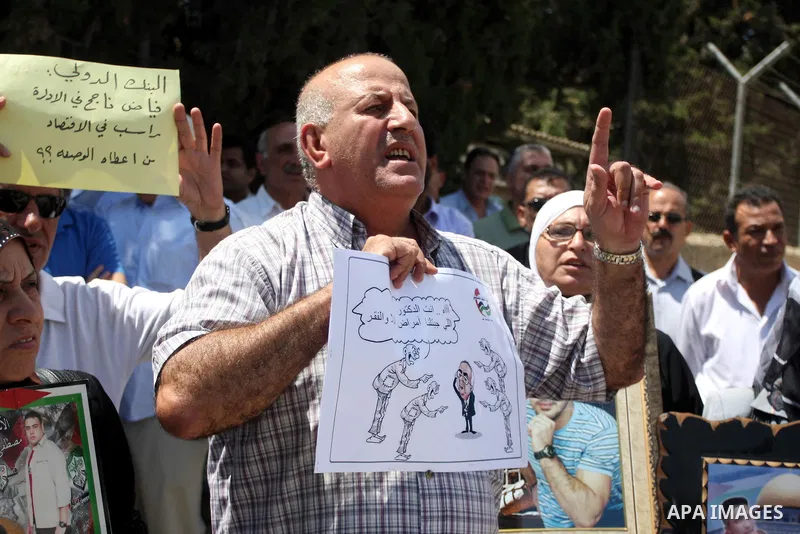 A Palestinian protester holds a sign during a demonstration against the the high expenses of Palestinian Prime Minister Salam Fayad, outside the office of the Presidency of the Government, in the West Bank city of Ramall...