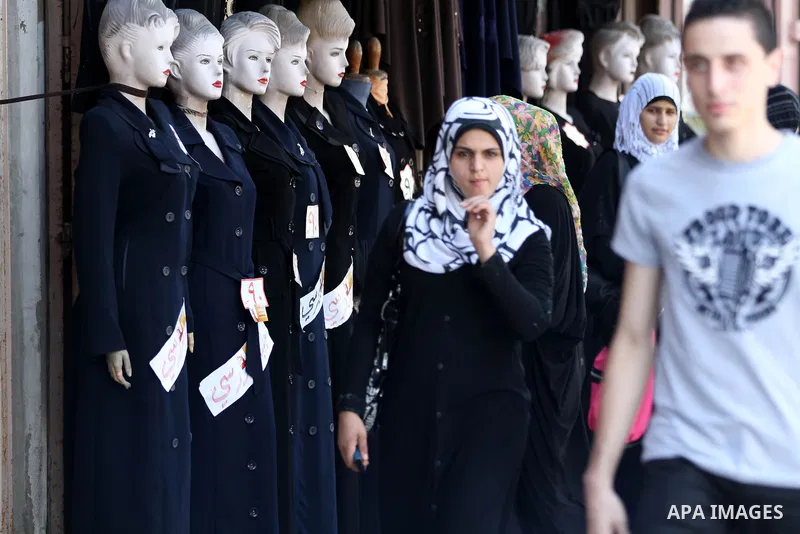 Palestinians walk past school uniforms displayed at a market in Gaza city on Aug 28, 2012. Next Sunday the First day for the new school year according to Palestinian Ministry of Education in the Gaza strip and the West B...