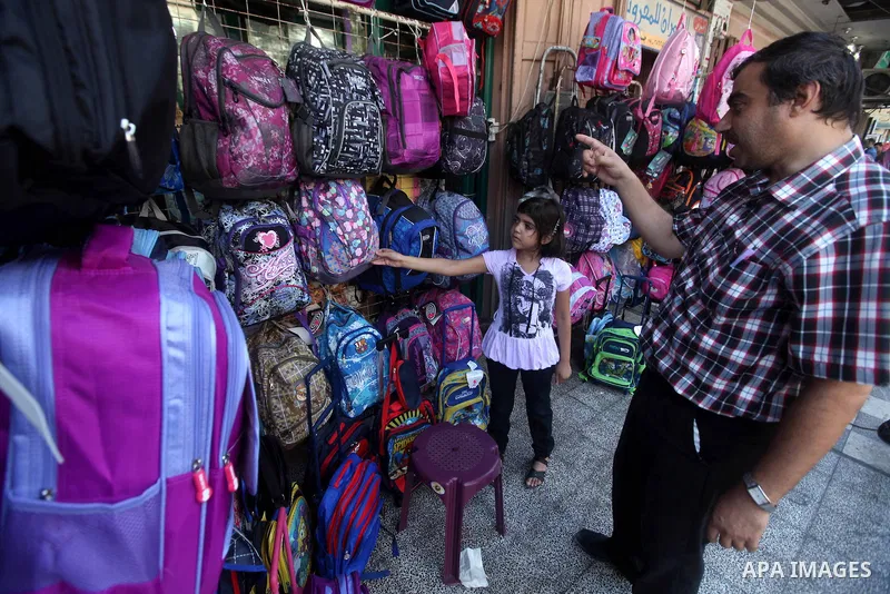 A Palestinian man with his daughter look at school bags displayed at a market in Gaza city on Aug 28, 2012. Next Sunday the First day for the new school year according to Palestinian Ministry of Education in the Gaza str...