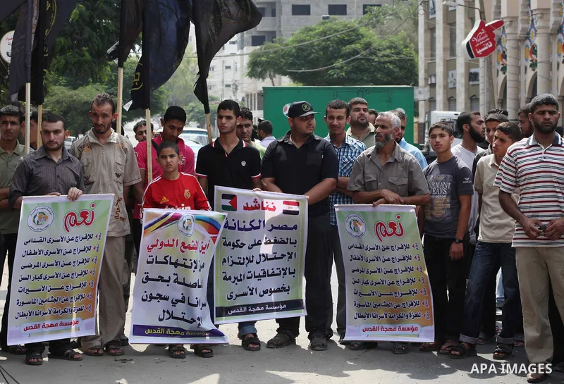 Palestinians hold up signs during a protest against administrative detention of Palestinian prisoners In Israeli jails, in front of the Red Cross headquarters in Gaza City on Aug. 29, 2012. Photo by Ashraf Amra