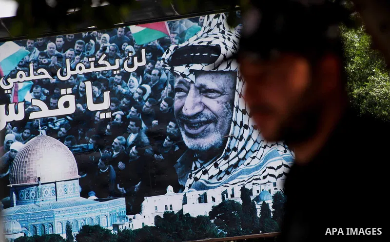 Palestinians walk in front of a mural of the Palestinian Leader Yasser Arafat in Gaza City, on Aug. 29, 2012. A French court has opened an investigation into the death of the late Palestinian leader Yasser Arafat in 2004...