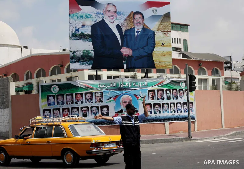 A Palestinian Hamas policeman organizes the traffic in front of a photograph released by Hamas, Egyptian President Mohammed Morsi, right, meets the Palestinian Prime Minister in Gaza, Ismail Haniyeh, in Gaza city on Aug....