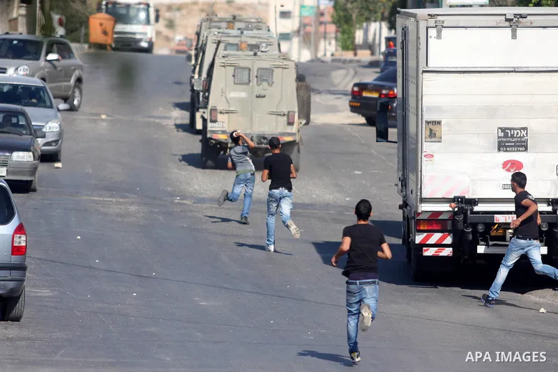 Palestinian youths throw stones at Israeli troops vehicles as they enter Om al-Sharayet neighborhood, in the West Bank city of Ramallah, Wednesday, Aug 29, 2012. Israeli soldiers raided a store in Om al-Sharayet and left...