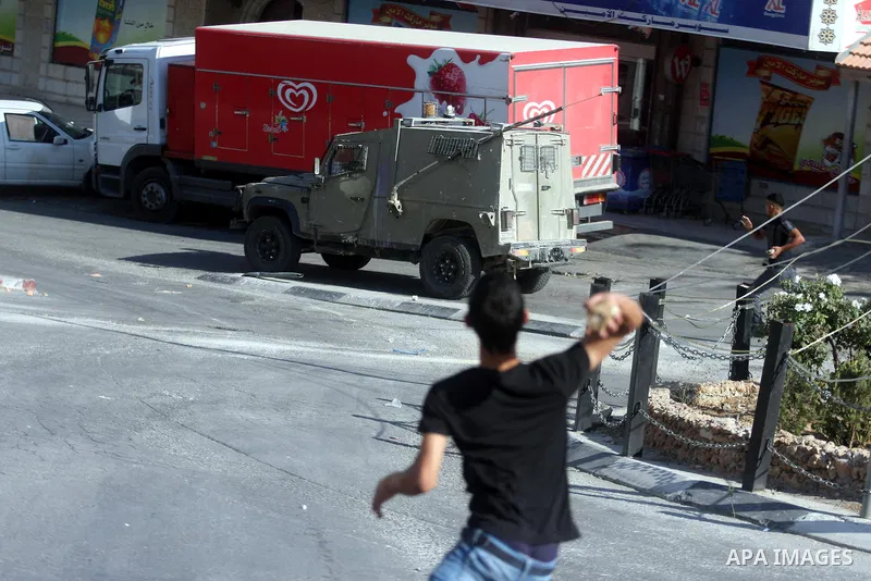 Palestinian youths throw stones at Israeli troops vehicles as they enter Om al-Sharayet neighborhood, in the West Bank city of Ramallah, Wednesday, Aug 29, 2012. Israeli soldiers raided a store in Om al-Sharayet and left...