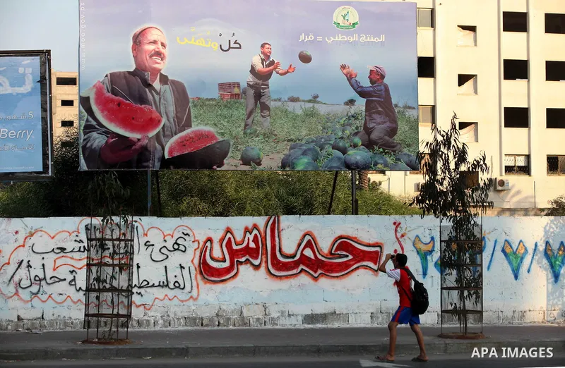A Palestinian youth takes a picture with his mobile phone for a placard released by Hamas Government reading in Arabic: "National products = Decision", in Gaza city, on Aug 28, 2012. The Ministry of Economy in Gaza start...