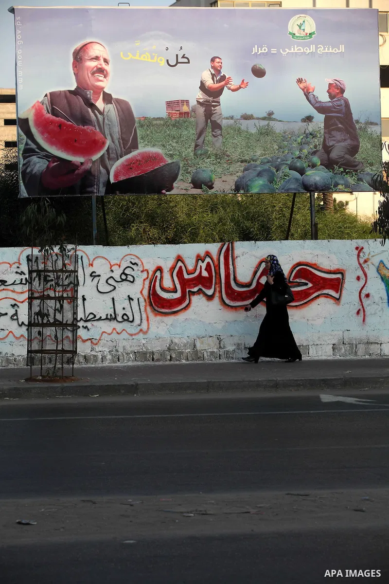 A Palestinian woman walks pass a placard released by Hamas Government reading in Arabic: "National products = Decision", in Gaza city, on Aug 28, 2012. The Ministry of Economy in Gaza started a campaign earlier to suppor...