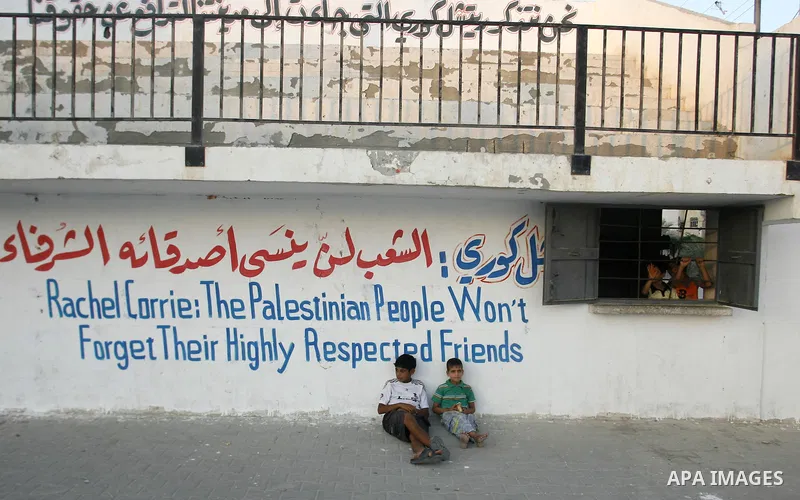 Palestinian boys sits at a refugee camp in Rafah, in the southern Gaza Strip and watch a local football match, named the "Rachel Corrie Cup", in honour of the US peace activist who was run over by an Israeli bulldozer du...