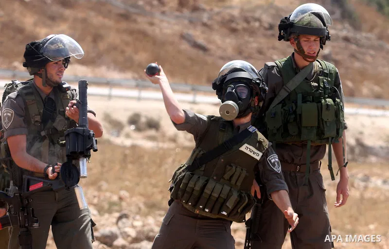 An Israeli soldier fires tear gas towards Palestinian demonstrators during clashes during a protest against the expansion of the nearby Jewish settlement of Halamish, in the West Bank village of Nabi Saleh, near Ramallah...
