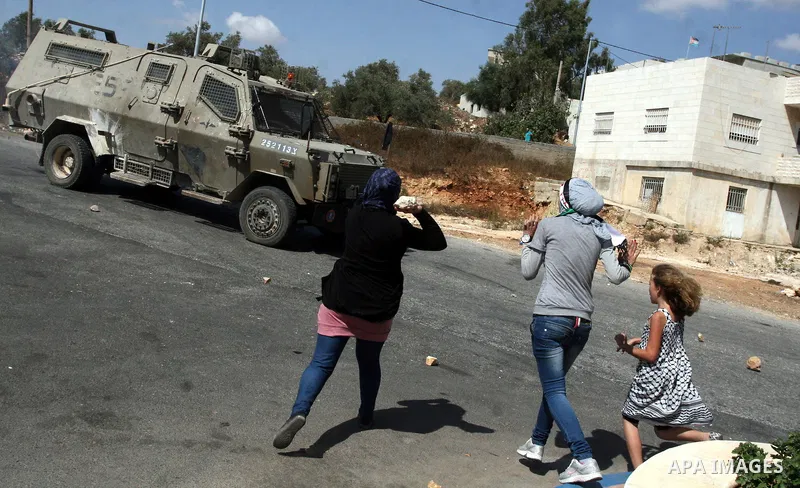Palestinian Girls throws stones towards an Israeli military vehicle during a protest against the confiscation of Palestinian land to expand Jewish settlements in the West Bank village of Nabi Saleh near Ramallah on Augus...