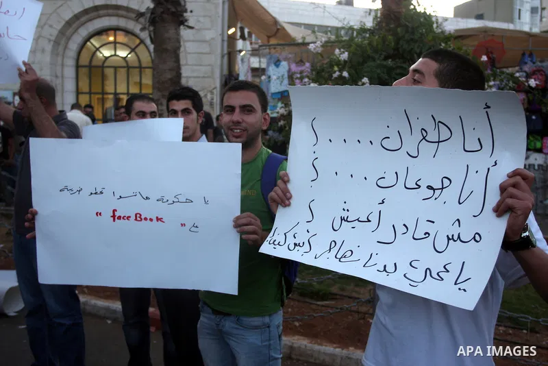 Palestinian protesters hold signs during a demonstration against the price rises, in the West Bank city of Ramallah, on September 02, 2012. Photo by Issam Rimawi