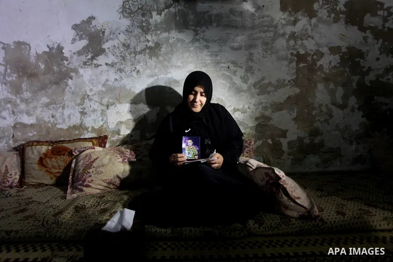 Palestinian Nadia Abu Nada holds a picture of her son Ihab Abu Nada at her home in the Shati refugee camp in Gaza City, Monday, Sept. 3, 2012. The death of a young Gaza man who set himself on fire because he could not fi...