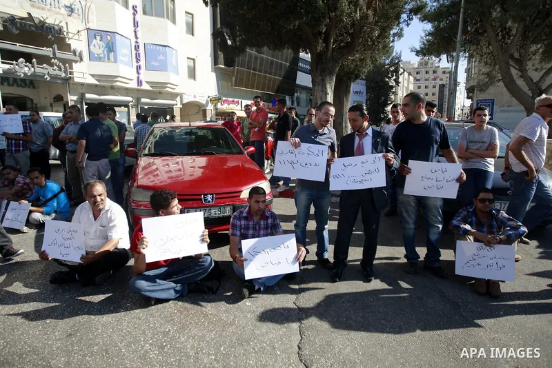 Palestinians hold placards against prime minister Salam Fayyad during a protest against the hight cost of living in the West Bank city of Ramallah on September 4, 2012. Photo by Issam Rimawi