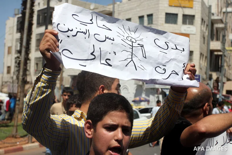 Palestinians hold placards against prime minister Salam Fayyad during a protest against the hight cost of living in the West Bank city of Ramallah on September 5, 2012. Photo by Issam Rimawi