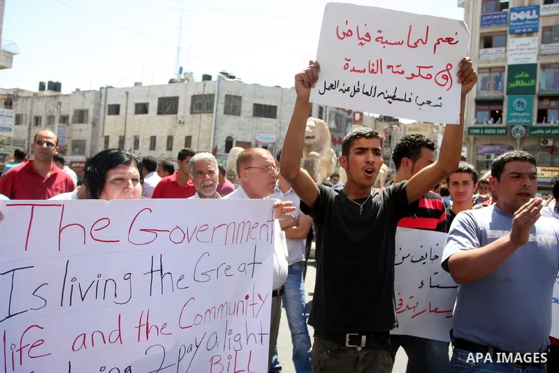 Palestinians hold placards against prime minister Salam Fayyad during a protest against the hight cost of living in the West Bank city of Ramallah on September 5, 2012. Photo by Issam Rimawi