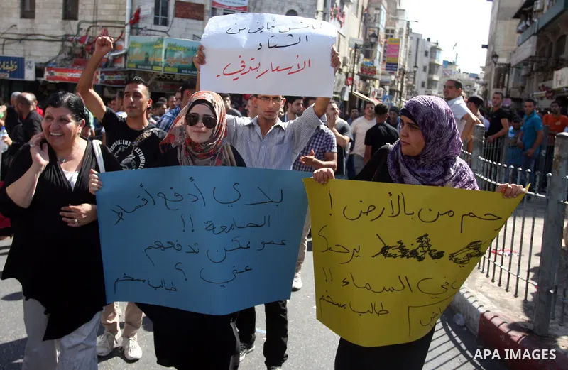 Palestinians hold placards against prime minister Salam Fayyad during a protest against the hight cost of living in the West Bank city of Ramallah on September 5, 2012. Photo by Issam Rimawi
