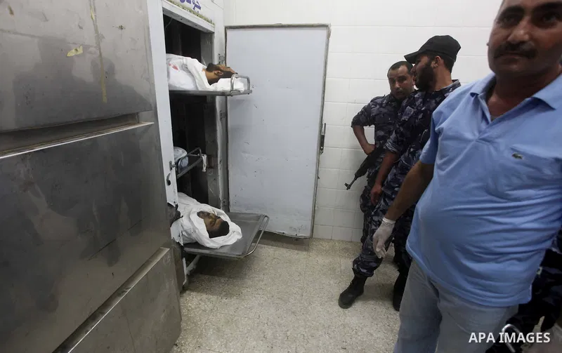 Palestinians stand by the body of one of three Palestinian militants killed in an Israeli airstrike earlier on September 5, 2012, at the morgue of the al-Aqsa hospital in Deir al-Balah, Gaza strip center. Photo by Ashraf...