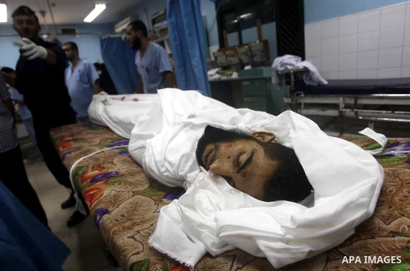 Palestinians stand by the body of one of three Palestinian militants killed in an Israeli airstrike earlier on September 5, 2012, at the morgue of the al-Aqsa hospital in Deir al-Balah, Gaza strip center. Photo by Ashraf...