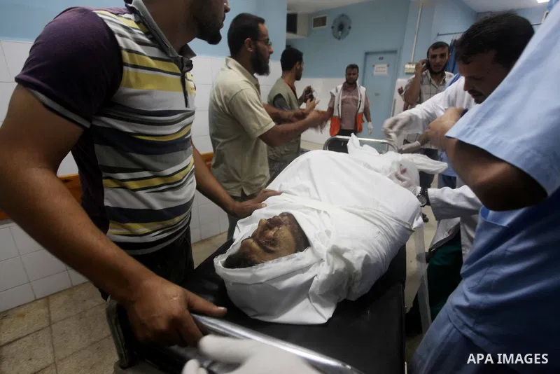 Palestinians stand by the body of one of three Palestinian militants killed in an Israeli airstrike earlier on September 5, 2012, at the morgue of the al-Aqsa hospital in Deir al-Balah, Gaza strip center. Photo by Ashraf...