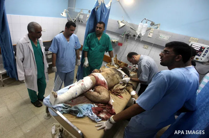 Palestinians stand by the body of one of three Palestinian militants killed in an Israeli airstrike earlier on September 5, 2012, at the morgue of the al-Aqsa hospital in Deir al-Balah, Gaza strip center. Photo by Ashraf...