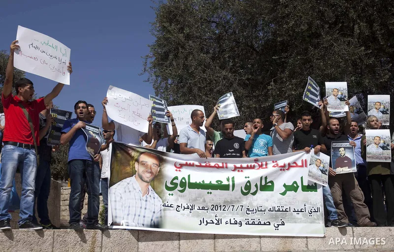 An Israeli soldier films Palestinian protesters as they shout slogans and hold portraits of prisoners in Israeli jails during a demonstration in solidarity with jailed Palestinians outside Damascus Gate in the old city o...