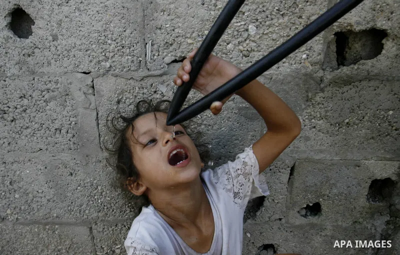 A Palestinian girl drinks water from hosepipe in front of her house in Rafah refugee camp in the southern of Gaza Strip, on September 08. 2012. Photo by Eyad Al Baba