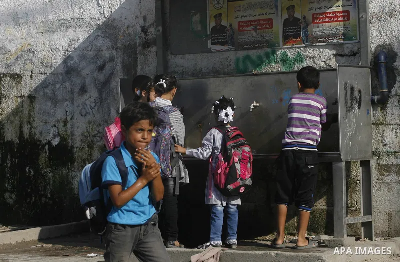 Palestinian students fill their bottles a potable water at a water purification station, in Rafah refugee camp in the southern of Gaza Strip, on September 08. 2012. Photo by Eyad Al Baba