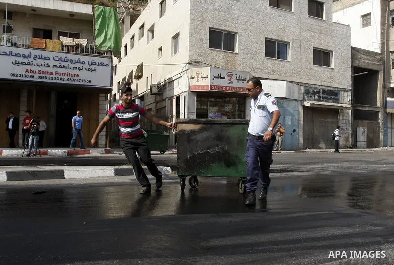 Palestinians policeman stand near burning tyres during a protest against the high cost of living in the West Bank city of Nablus September 10, 2012. Photo by Nedal Eshtayah