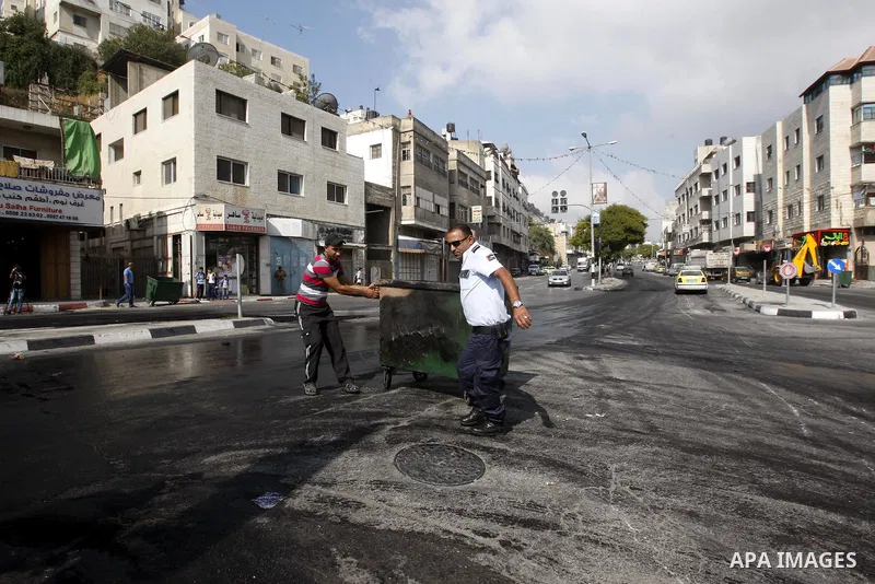 Palestinians policeman stand near burning tyres during a protest against the high cost of living in the West Bank city of Nablus September 10, 2012. Photo by Nedal Eshtayah