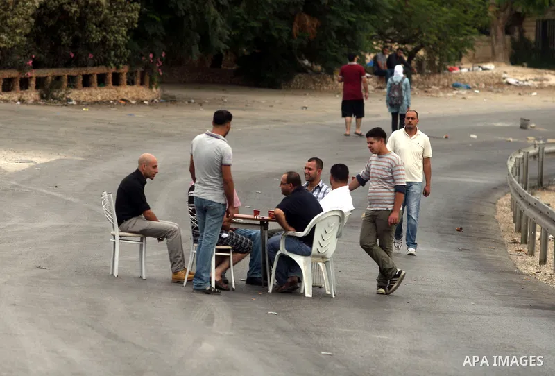 Palestinian men sit around a table as they block a street in the West Bank city of Ramallah during a protest against the high cost of living on September 10, 2012. Cities across the West Bank ground to a halt as transpor...