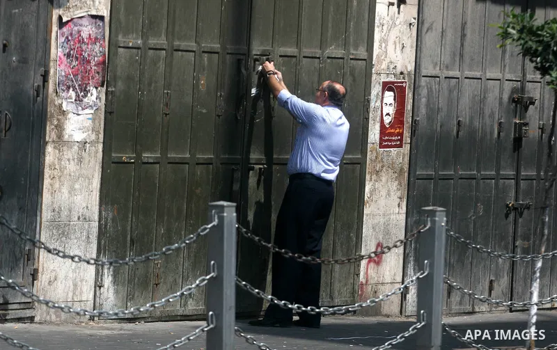 A Palestinian shop owner closes the door of his store during a protest against the high cost of living on September 10, 2012 in the West Bank city of Ramallah. Cities across the West Bank ground to a halt as transport un...