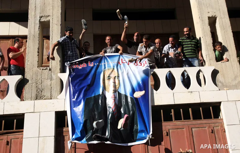 Palestinian protesters throw shoes on a portrait of Prime Minister Salam Fayyad during a demonstration against the high cost of living in the southern West Bank city of Hebron on September 10, 2012. The Palestinian Autho...
