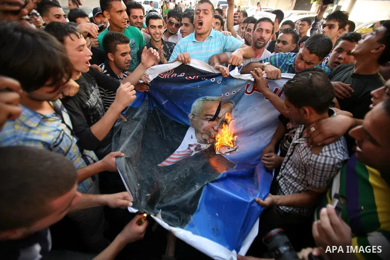 Palestinian protesters burn a portrait of Prime Minister Salam Fayyad during a demonstration against the high cost of living in the southern West Bank city of Hebron on September 10, 2012. The Palestinian Authority is un...