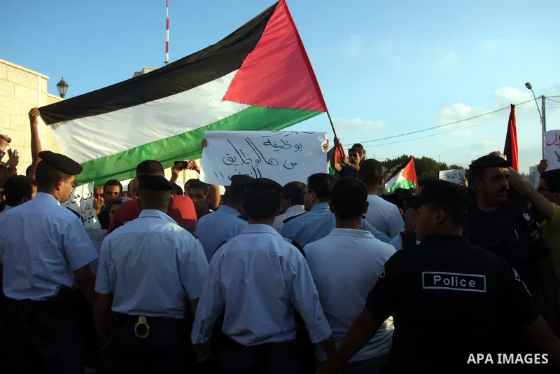 Palestinian police officers stand barrier in front of demonstrators during a protest against the Paris Protocol and the Oslo Agreement, both key accords which govern economic ties between Palestinians and Israelis, in th...
