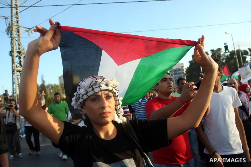 A Palestinian woman waves a national flag during a protest against the Paris Protocol and the Oslo Agreement, both key accords which govern economic ties between Palestinians and Israelis, in the West Bank city of Ramall...