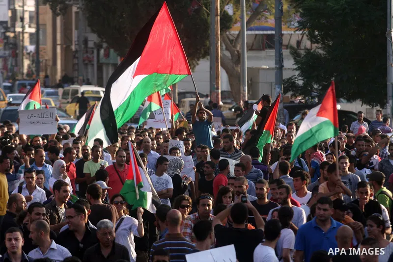 Palestinians wave their national flag during a protest against the Paris Protocol and the Oslo Agreement, both key accords which govern economic ties between Palestinians and Israelis, in the West Bank city of Ramallah o...