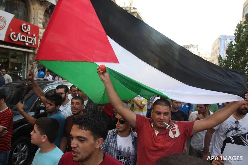 Palestinians wave their national flag during a protest against the Paris Protocol and the Oslo Agreement, both key accords which govern economic ties between Palestinians and Israelis, in the West Bank city of Ramallah o...