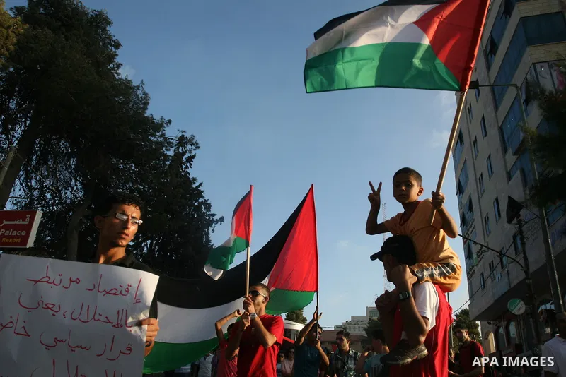 Palestinians wave their national flag during a protest against the Paris Protocol and the Oslo Agreement, both key accords which govern economic ties between Palestinians and Israelis, in the West Bank city of Ramallah o...