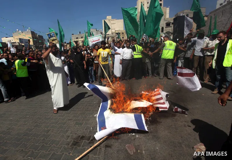 Palestinians burn the Israeli and the U.S. flags during a demonstration against the controversial film 'Innocence of Muslims' in Khan Younis southern Gaza strip, on September 14, 2012. The controversial low budget film r...