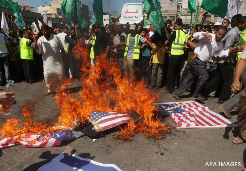 Palestinians burn the Israeli and the U.S. flags during a demonstration against the controversial film 'Innocence of Muslims' in Khan Younis southern Gaza strip, on September 14, 2012. The controversial low budget film r...